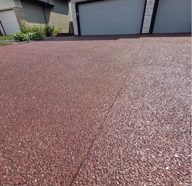 The same red aggregate driveway after sealing, with rich colour and glossy stone