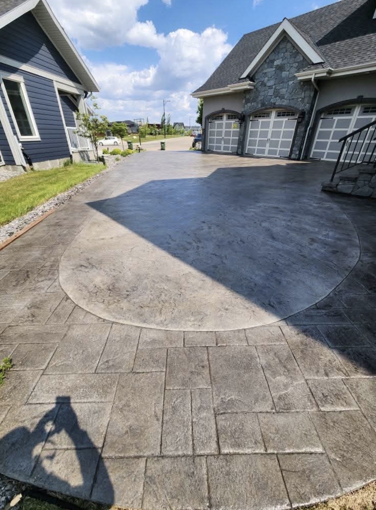 Concrete driveway with a stamped circular medallion and a freshly sealed wet-look finish