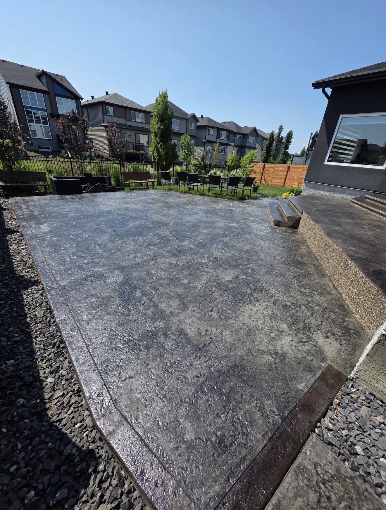 Large stamped concrete backyard patio and entry steps with a freshly sealed finish
