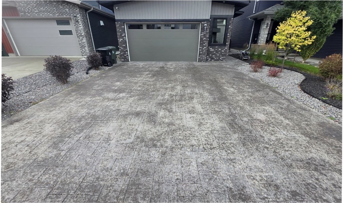Stamped concrete driveway with a faded, washed-out ashlar slate pattern before resealing