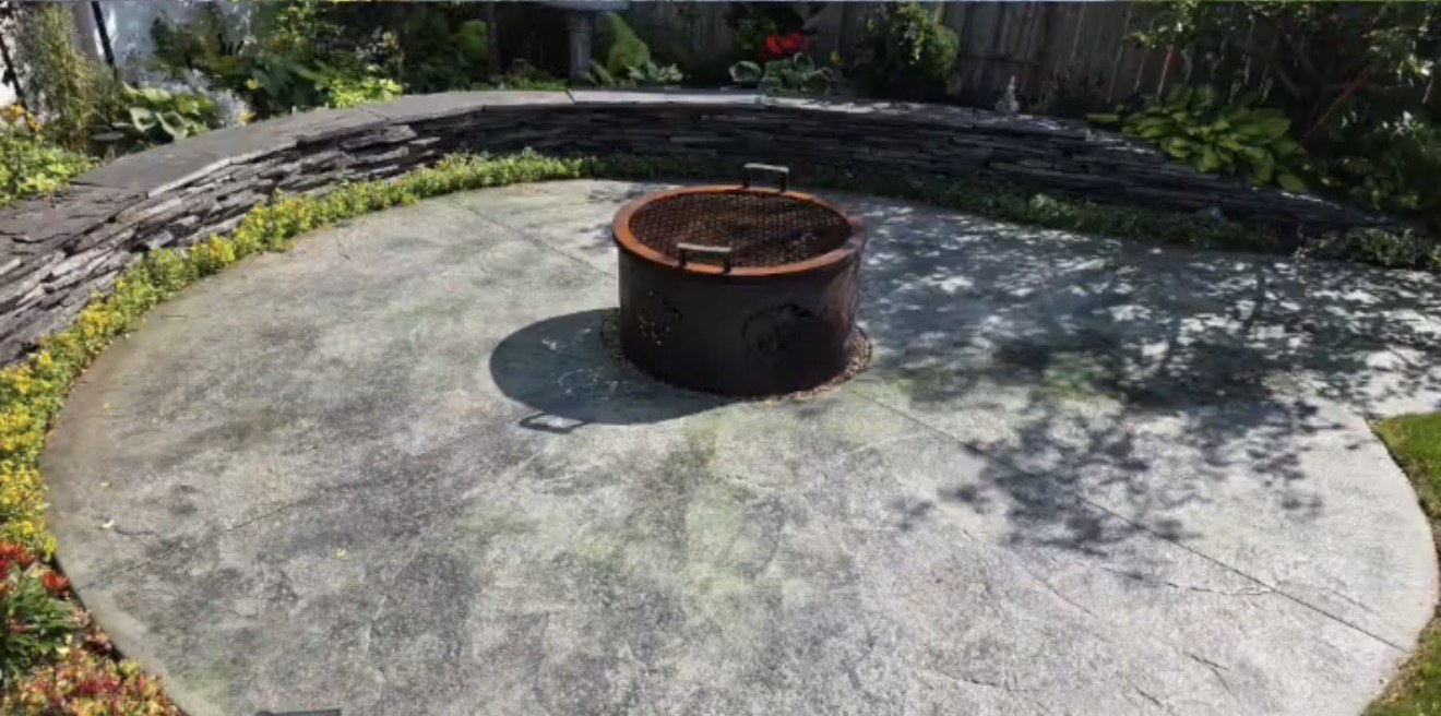 Round stamped concrete patio with a fire pit before resealing