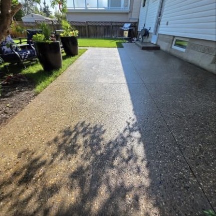 Freshly sealed exposed aggregate side path beside a house