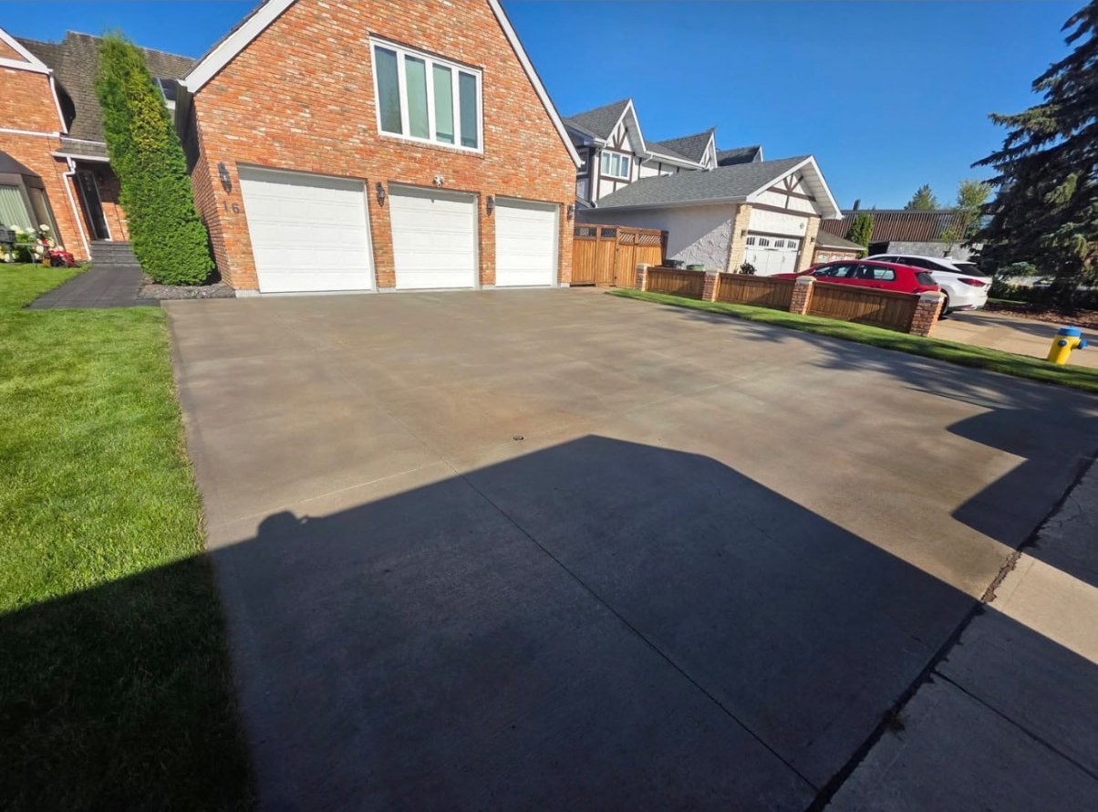 The same triple-garage driveway after sealing with a darker, even finish